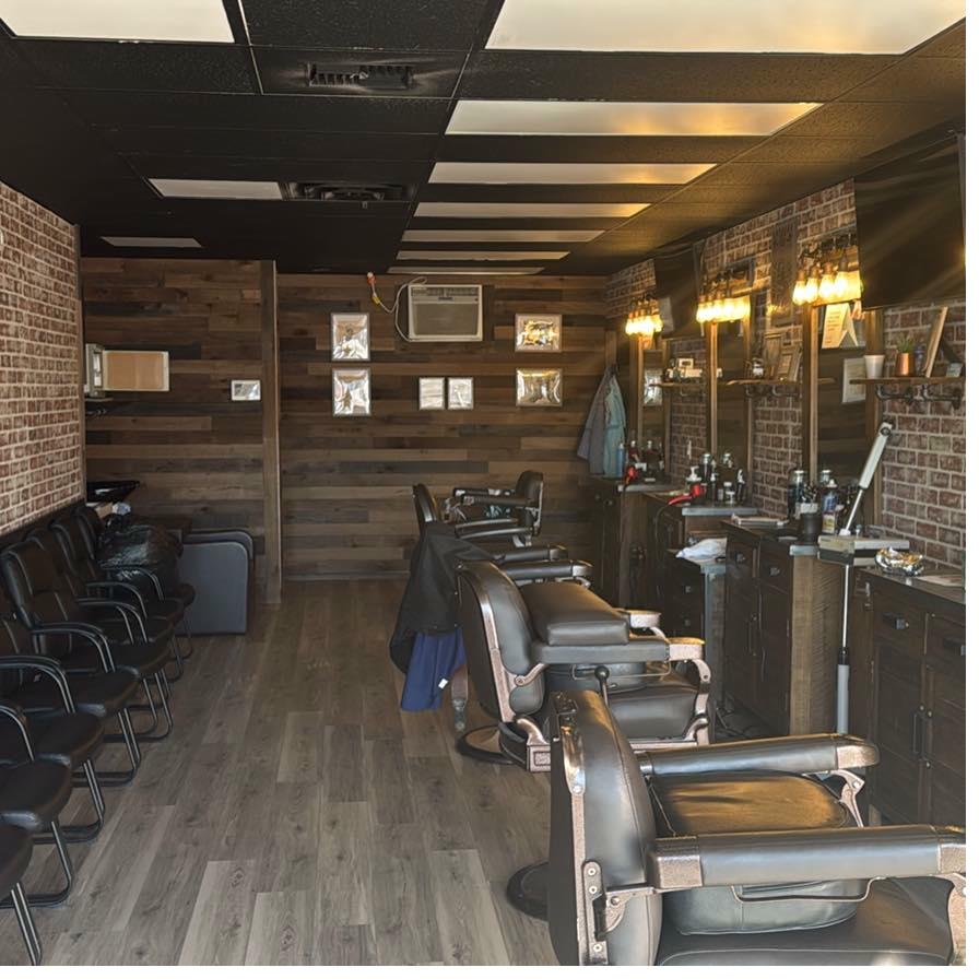 Fade N' Shave Barber Shop interior — remodeled with brick walls, leather chairs, and warm Edison bulb lighting
